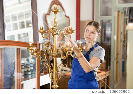 Woman restores vintage chandelier in the restoration workshop Woman restores vintage chandelier in the restoration workshop 136065906