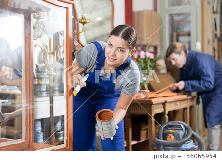Professional furniture restorer renewing vintage chest of drawers in workshop 136065954