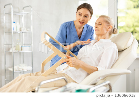 Old woman having consultation about face aesthetic while looking in the mirror 136066018