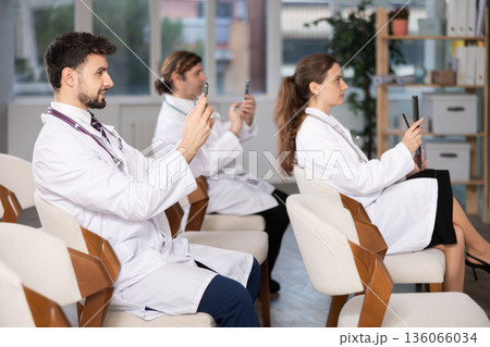 Medical students or doctors using mobile phones to scan QR-code during interactive lesson 136066034