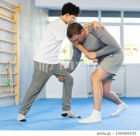 Man and boy teenager training self-defense techniques 136066035