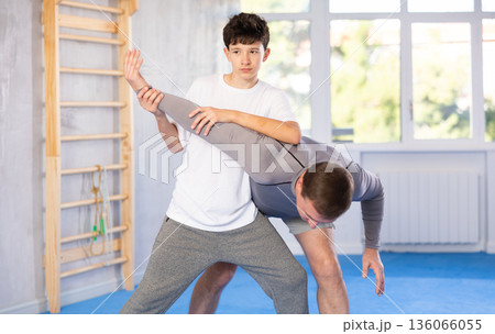 Teenage boy and middle-aged man training arm twist technique during self-defense courses Teenage boy and middle-aged man training arm twist technique during self-defense courses 136066055