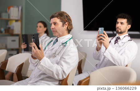 Medical students or doctors using mobile phones to scan QR-code during interactive lesson 136066229