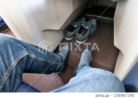 Inflight business class passenger with ample leg room took off shoes during flight for comfort travel 136067395