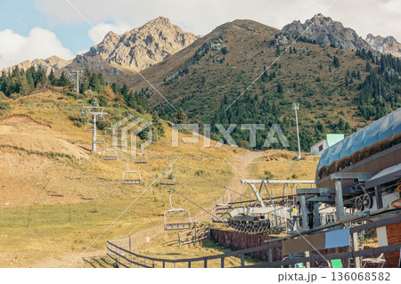 scenic view of mountains with a cable car station. The landscape features green hills and a clear blue sky, ideal for a vacation getaway. scenic view of mountains with a cable car station. The landscape features green hills and a clear blue sky, ideal for a vacation getaway. 136068582