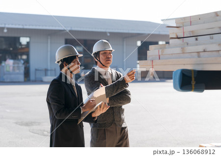 材木所で木材を見るスーツの男性たち 136068912