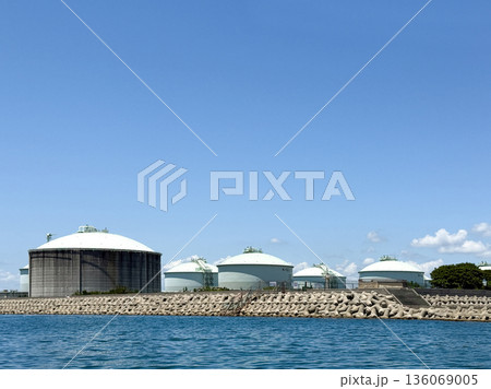 海沿いに並ぶ大型貯蔵タンクと青空の産業風景 136069005
