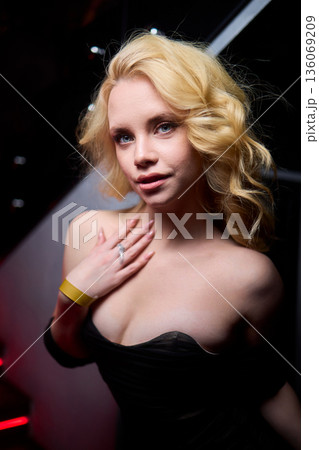 Elegant night scene, Sophisticated female model exuding confidence during evening event, Fashion forward woman highlighted by striking red lighting at glamorous social gathering 136069209