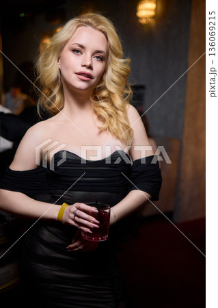 Elegant night scene, Sophisticated female model exuding confidence during evening event, Fashion forward woman highlighted by striking red lighting at glamorous social gathering Elegant night scene, Sophisticated female model exuding confidence during evening event, Fashion forward woman highlighted by striking red lighting at glamorous social gathering 136069215