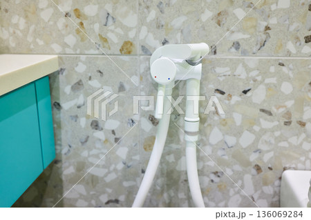 Modern ceramic fixture with flexible hose, Close view of hygienic bathroom cleaning equipment, Contemporary sanitary fixture featuring spray connected to wall valve 136069284
