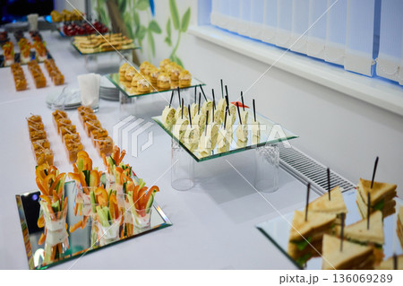 Elegant dining presentation, Sophisticated arrangement of canapes on stylish table setting, Exquisite black trays with gourmet delicacies showcased in upscale event ambiance 136069289