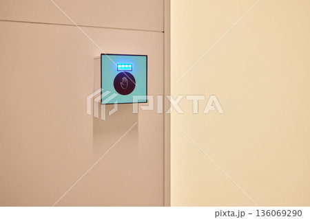 This is a modern smart touch sensor device installed on a wall, featuring a blue LED indicator This is a modern smart touch sensor device installed on a wall, featuring a blue LED indicator 136069290