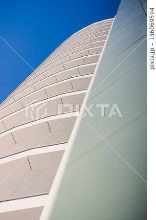 Innovative urban building designs. Modern constructions with unique balcony features. Contemporary city structures showcasing distinctive curved balconies and green glass 136069594