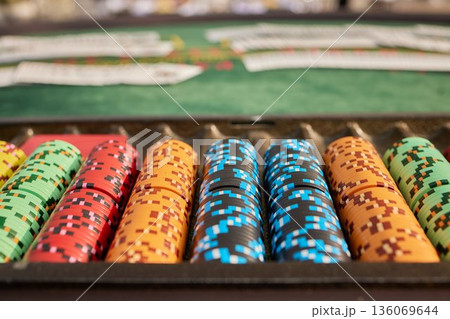 Multicolored poker chips laid out on felt table with blurred casino background, Vibrant poker chips organized on felt with shallow focus and anticipation filled casino setting Multicolored poker chips laid out on felt table with blurred casino background, Vibrant poker chips organized on felt with shallow focus and anticipation filled casino setting 136069644