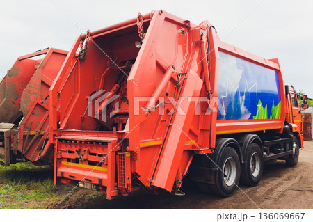 Streetside trash collection truck, Municipal refuse collection vehicle in operation, City municipal waste collection vehicle stationed beside street during overcast morning 136069667