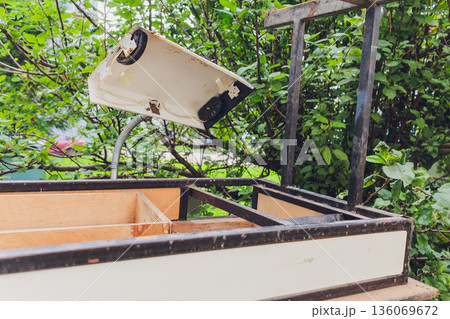 DIY project involving old light fixture in overgrown garden environment, Nostalgic outdoor scene depicting discarded lantern with tangled wiring and weathered materials 136069672