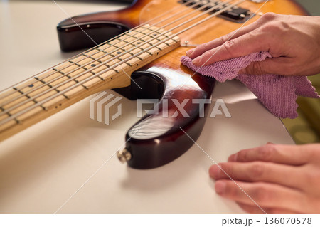 Closeup of guitar care and preparation process with studio lighting, Careful guitar body polishing and setup under professional studio lights before stage performance 136070578