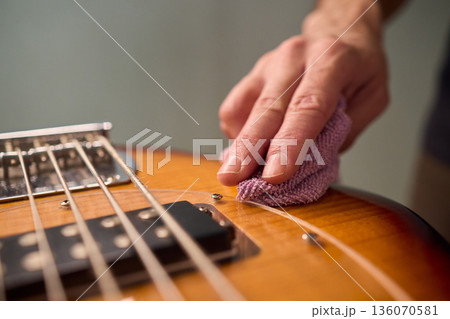 Closeup of guitar care and preparation process with studio lighting, Careful guitar body polishing and setup under professional studio lights before stage performance Closeup of guitar care and preparation process with studio lighting, Careful guitar body polishing and setup under professional studio lights before stage performance 136070581