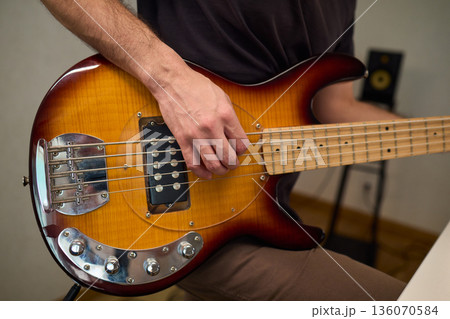 Musician working in cozy studio, Casual musician practicing bass with effects and accents, Relaxed bassist intensely rehearsing in warmly lit home recording environment 136070584