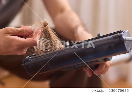 Closeup of technician servicing vacuum brush components carefully. Workshop scene showing technician disassembling and inspecting vacuum brush head meticulously 136070686