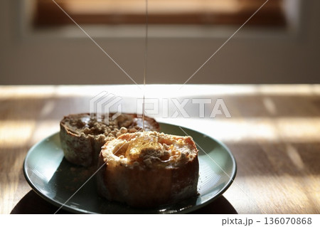 全粒粉のリュスティックのバターきな粉パンにハチミツを垂らしているところ 全粒粉のリュスティックのバターきな粉パンにハチミツを垂らしているところ 136070868