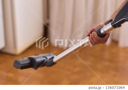 Hardwood floor vacuum head gliding across polished parquet, closeup of nozzle brushing wood grain, warm lighting, quiet household cleaning, gentle maintenance mood 136071064