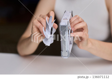 Detailed scene with technician disassembling small desktop fan carefully. Precise hands removing cover of desk fan during technical inspection with focused lighting Detailed scene with technician disassembling small desktop fan carefully. Precise hands removing cover of desk fan during technical inspection with focused lighting 136071112