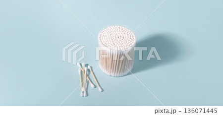Cotton swabs in container and scattered on blue background 136071445