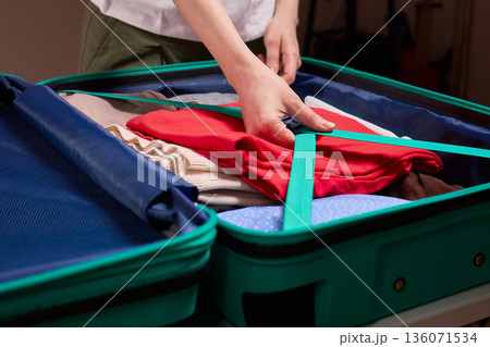 Adjusting luggage straps for safe travel, Careful setup of travel gear with strap focus, Ensuring secure strap positioning inside luggage before beginning your journey 136071534