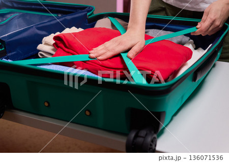 Adjusting luggage straps for safe travel, Careful setup of travel gear with strap focus, Ensuring secure strap positioning inside luggage before beginning your journey Adjusting luggage straps for safe travel, Careful setup of travel gear with strap focus, Ensuring secure strap positioning inside luggage before beginning your journey 136071536
