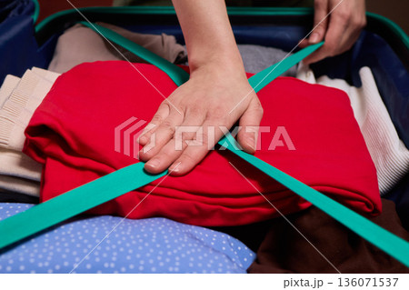 Adjusting luggage straps for safe travel, Careful setup of travel gear with strap focus, Ensuring secure strap positioning inside luggage before beginning your journey 136071537