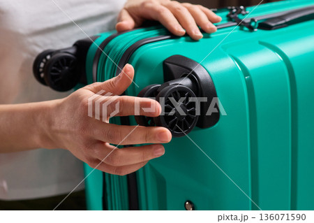 Inspecting suitcase wheels for strength and smooth operation before travel, Traveler thoroughly assesses condition and reliability of suitcase wheels for upcoming journey Inspecting suitcase wheels for strength and smooth operation before travel, Traveler thoroughly assesses condition and reliability of suitcase wheels for upcoming journey 136071590