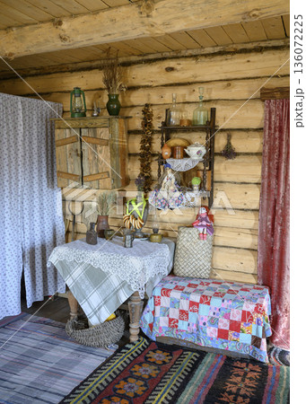Wooden shelf with dishes and national dolls in the interior of a 19th-century Russian hut 136072225