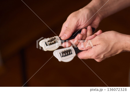 Household brushes examined closely, Two brushes analyzed in indoor setting, Person holding two black brushes inspecting bristle arrangement for household cleaning purposes Household brushes examined closely, Two brushes analyzed in indoor setting, Person holding two black brushes inspecting bristle arrangement for household cleaning purposes 136072328
