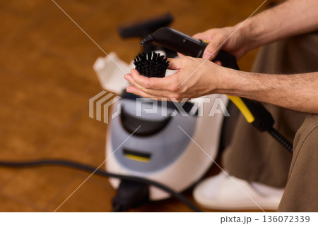 Household brushes examined closely, Two brushes analyzed in indoor setting, Person holding two black brushes inspecting bristle arrangement for household cleaning purposes 136072339