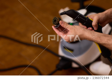 Household brushes examined closely, Two brushes analyzed in indoor setting, Person holding two black brushes inspecting bristle arrangement for household cleaning purposes 136072344