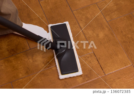 Steam cleaning device being prepared for upholstery and grout cleaning tasks. Focus on textured grip and soft plastic with warm background indicating household maintenance 136072385