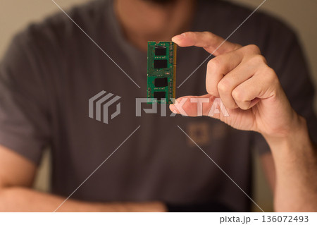 Individual carefully inspecting SODIMM memory module in detailed review, Technician performing detailed visual assessment of RAM stick with neutral lighting and focused attention Individual carefully inspecting SODIMM memory module in detailed review, Technician performing detailed visual assessment of RAM stick with neutral lighting and focused attention 136072493