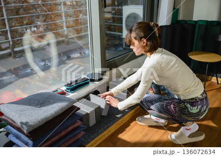 Woman arranging yoga blocks in studio before practice Woman arranging yoga blocks in studio before practice 136072634