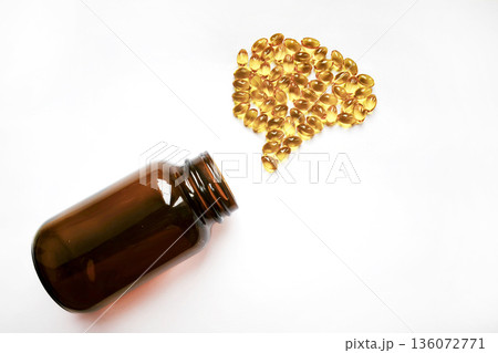Omega-3 goldfish oil capsules spilling from a glass jar in the shape of a human brain on a white background with space for text. Brain health concept. Omega-3 goldfish oil capsules spilling from a glass jar in the shape of a human brain on a white background with space for text. Brain health concept. 136072771