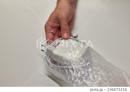 Technician examining charger carefully, Closeup of hands inspecting laptop cable, Meticulous technician performing detailed inspection of laptop power supply before packaging Technician examining charger carefully, Closeup of hands inspecting laptop cable, Meticulous technician performing detailed inspection of laptop power supply before packaging 136073258