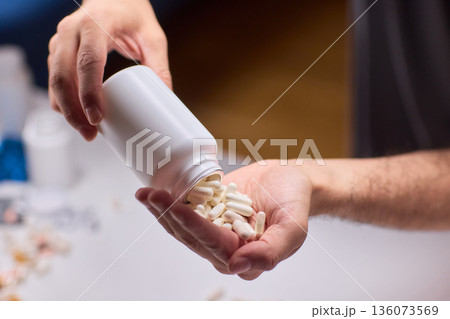 Closeup of caregiver preparing medication in warm bathroom environment, Wrist and fingers shown as caregiver arranges pills from bottle for daily dosage in soothing lighting Closeup of caregiver preparing medication in warm bathroom environment, Wrist and fingers shown as caregiver arranges pills from bottle for daily dosage in soothing lighting 136073569