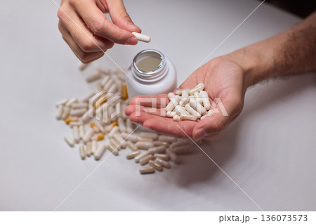 Closeup of caregiver preparing medication in warm bathroom environment, Wrist and fingers shown as caregiver arranges pills from bottle for daily dosage in soothing lighting Closeup of caregiver preparing medication in warm bathroom environment, Wrist and fingers shown as caregiver arranges pills from bottle for daily dosage in soothing lighting 136073573