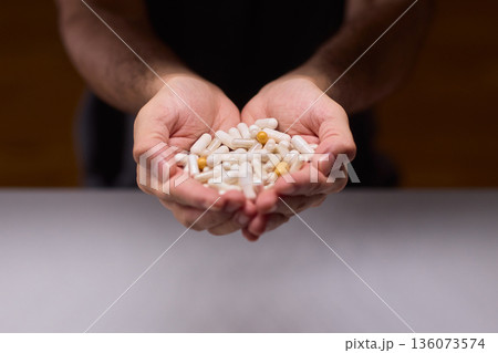 Closeup of caregiver preparing medication in warm bathroom environment, Wrist and fingers shown as caregiver arranges pills from bottle for daily dosage in soothing lighting 136073574