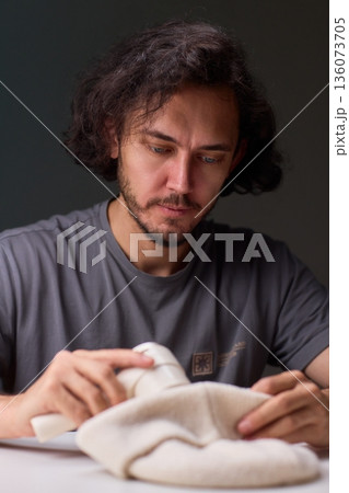 Close view of lint tool on wool, Man using lint roller to clean wool hat texture, Detailed scene of hand grooming fuzz from soft knitted wool hat with lint roller Close view of lint tool on wool, Man using lint roller to clean wool hat texture, Detailed scene of hand grooming fuzz from soft knitted wool hat with lint roller 136073705