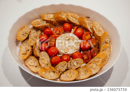 Camembert cheese baked with tomatoes and baguette, herbs and garlic. An excellent appetizer for wine. View from above.  136073739