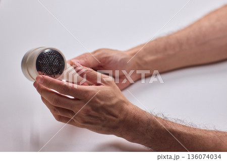 Close view of lint tool on wool, Man using lint roller to clean wool hat texture, Detailed scene of hand grooming fuzz from soft knitted wool hat with lint roller Close view of lint tool on wool, Man using lint roller to clean wool hat texture, Detailed scene of hand grooming fuzz from soft knitted wool hat with lint roller 136074034