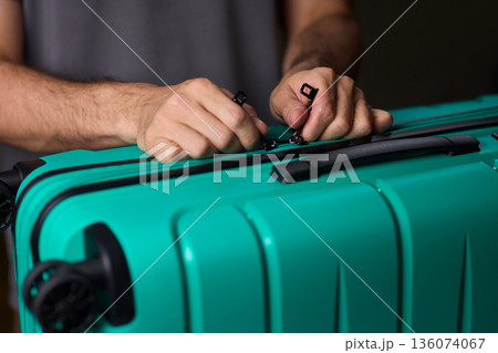 Secure suitcase with combo lock, Hands set combination on teal suitcase with textured surface, Closeup of hands adjusting numeric lock on stylish teal travel suitcase Secure suitcase with combo lock, Hands set combination on teal suitcase with textured surface, Closeup of hands adjusting numeric lock on stylish teal travel suitcase 136074067