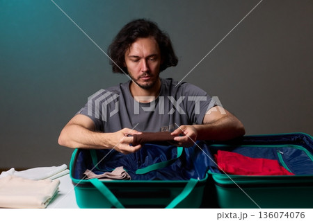 Organizing clothes before travel, Traveler arranges garments meticulously in their suitcase, An individual smoothly folds clothing and organizes suitcase for upcoming departure 136074076