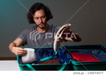 Organizing clothes before travel, Traveler arranges garments meticulously in their suitcase, An individual smoothly folds clothing and organizes suitcase for upcoming departure Organizing clothes before travel, Traveler arranges garments meticulously in their suitcase, An individual smoothly folds clothing and organizes suitcase for upcoming departure 136074077